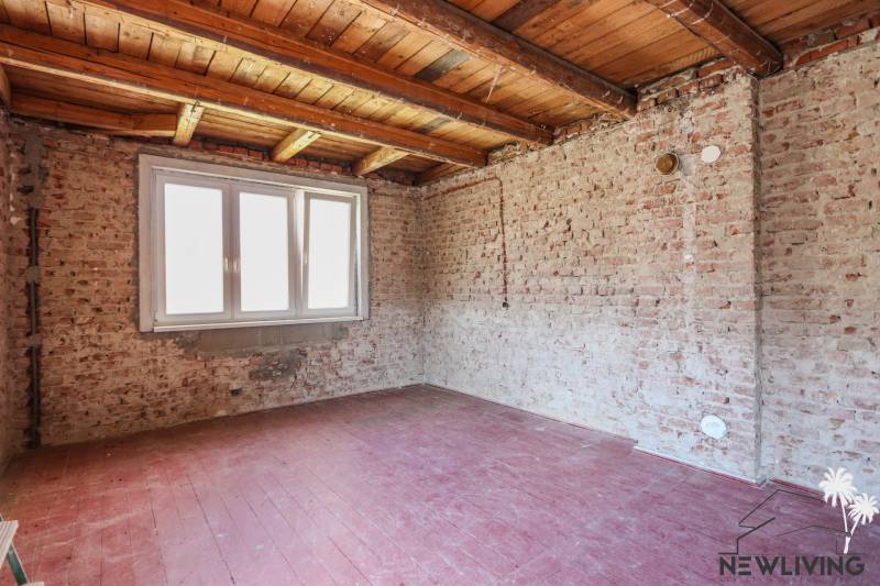 Családi ház belső tere téglafalakkal és ablakkal, fa dekorációjú padlóval.