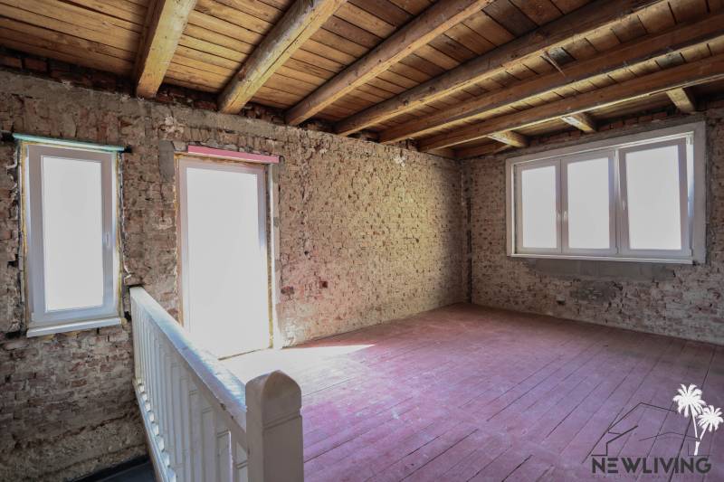 Családi ház belső tere csupasz téglafalakkal, fa mennyezettel és padlóval.