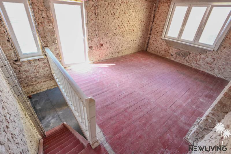 Lépcsőház és téglafalak családi házban nagy ablakokkal és padlóval.