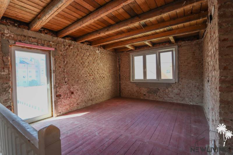 Családi ház belső tere téglafalakkal és nagy ablakokkal, fa dekorációjú padlóval.