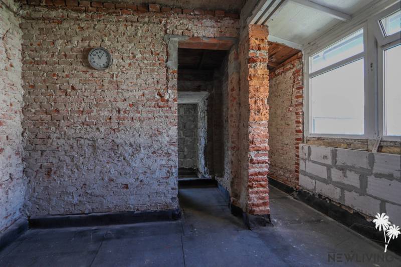 Vakolatlan téglafalak és egyszerű belső tér egy családi házban ablakkal.