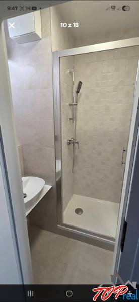 Fürdőszoba modern zuhanyzóval és mosdóval a garzonlakásban.