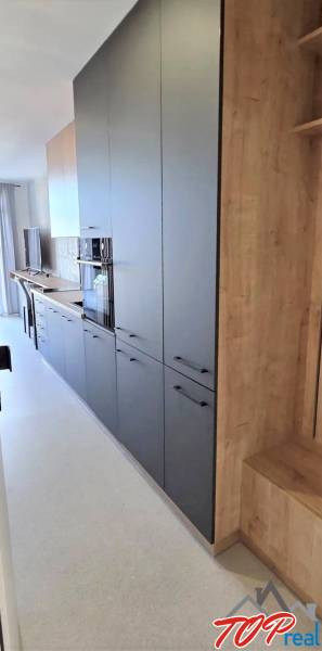 Konyhapult garzonlakásban sötét szekrényekkel és világos, fa mintázatú padlóval.