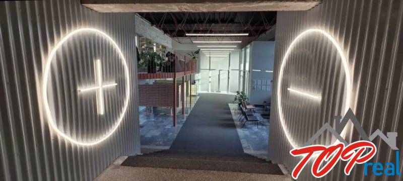 Belső tér lépcsőkkel, kör alakú világítással a falakon és üveg válaszfallal a háttérben.