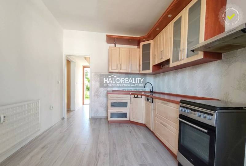 Konyha egy háromszobás lakásban, fa dekor padlóval és világos bútorokkal.