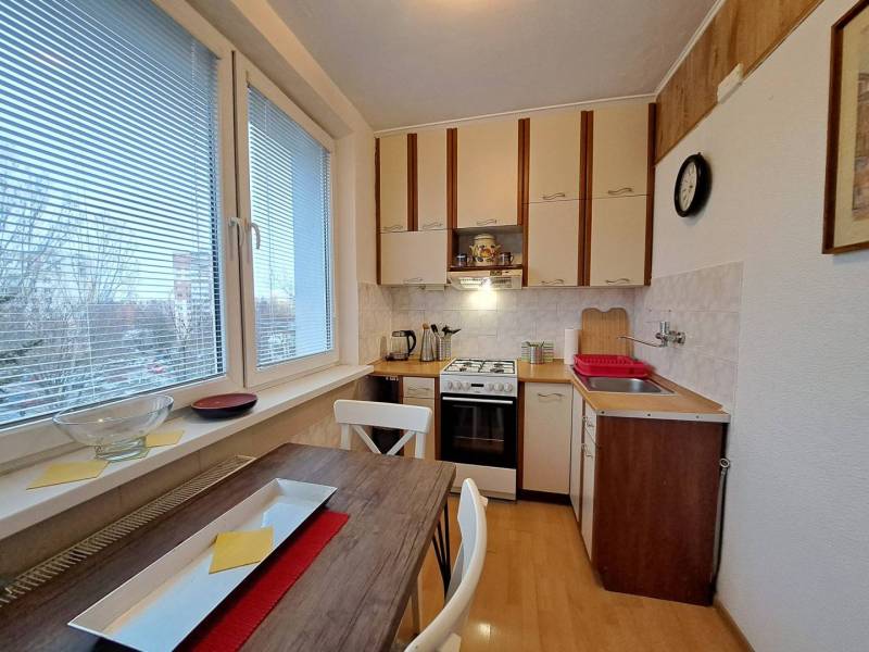 Konyha egy kétszobás lakásban gáz tűzhellyel és fa mintázatú padlóval.