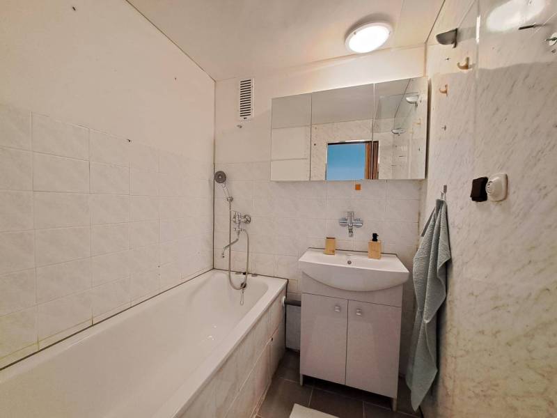 Fürdőszoba egy kétszobás lakásban káddal, mosdóval és tükörrel.