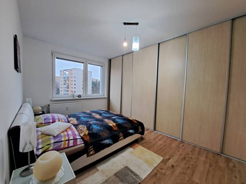 Hálószoba egy kétszobás lakásban fa dekor padlóval és nagy beépített szekrénnyel.