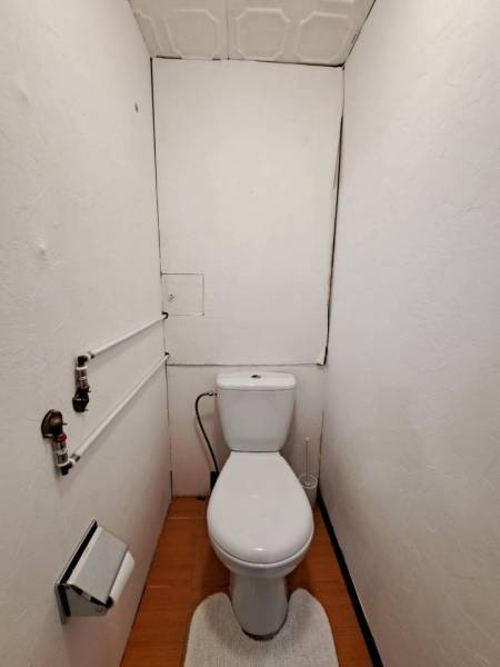 Fürdőszoba WC-vel és fa dekoros padlóval egy kétszobás lakásban.