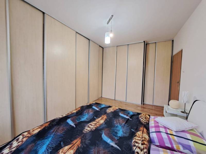 Hálószoba nagy beépített szekrénnyel és ággyal egy kétszobás lakásban.