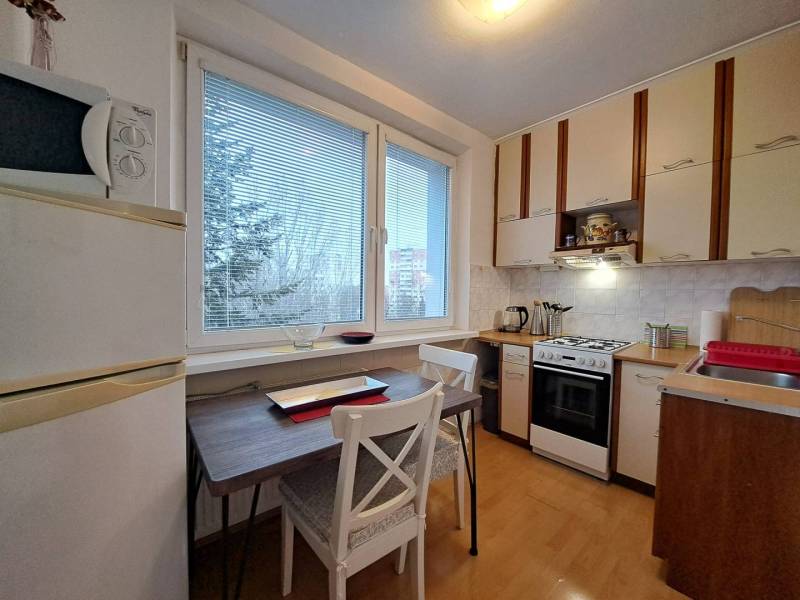 Konyha kétszobás lakásban fa mintázatú padlóval és kilátással.