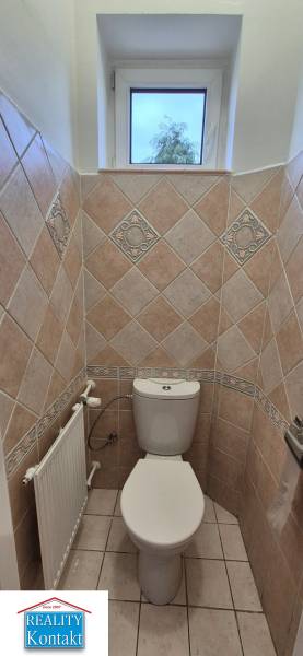 Fürdőszoba WC-vel egy háromszobás lakásban, csempézett falak és ablak.