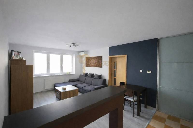 Nappali egy háromszobás lakásban sarokkanapéval és fa dekorációjú padlóval.