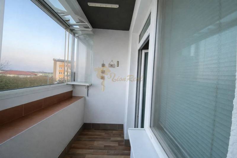 Üvegezett loggia egy 3 szobás lakásban, fa hatású padlóval.