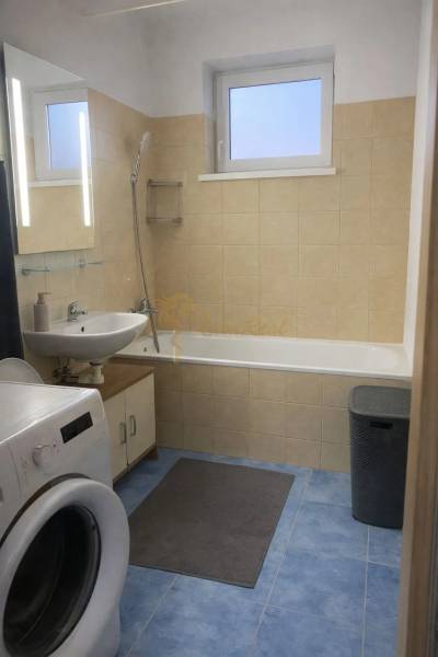 Fürdőszoba káddal, mosdóval és mosógéppel egy háromszobás lakásban, kék csempékkel.