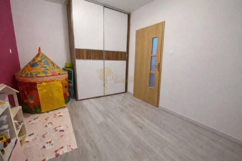 Gyerekszoba fa mintázatú padlóval és színes sátorral egy háromszobás lakásban.