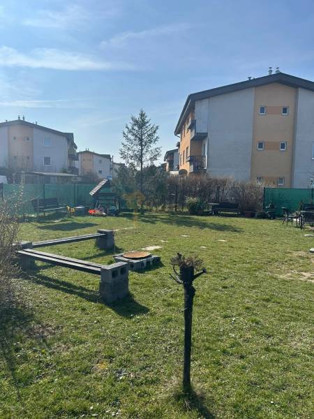 Füves terület padokkal és lakóházakkal az M.R.Štefánika utcában, Most pri Bratislave.