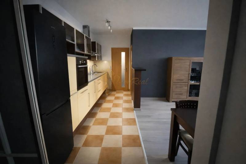 Konyha egy 3 szobás lakásban konyhabútorral és étkezőasztallal, padló csempével.