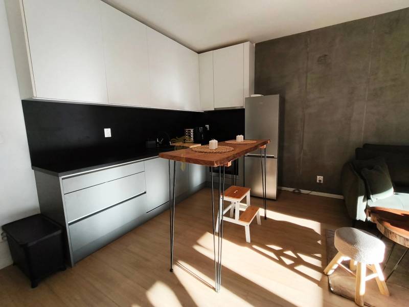 Konyha egy kétszobás lakásban sötét fallal és fa dekorációjú padlóval.