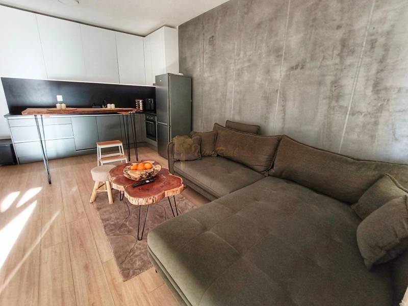 Konyha és nappali rész egy kétszobás lakásban, fa dekorú padlóval.