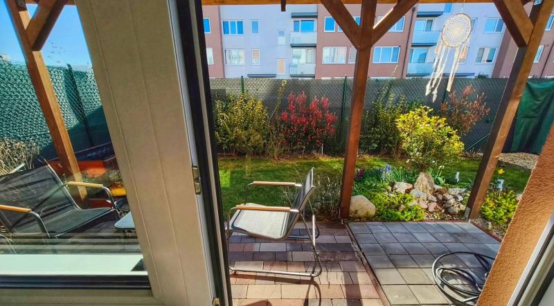 Kert terasszal és székekkel a kétszobás lakásban, kilátás az üvegajtón keresztül.