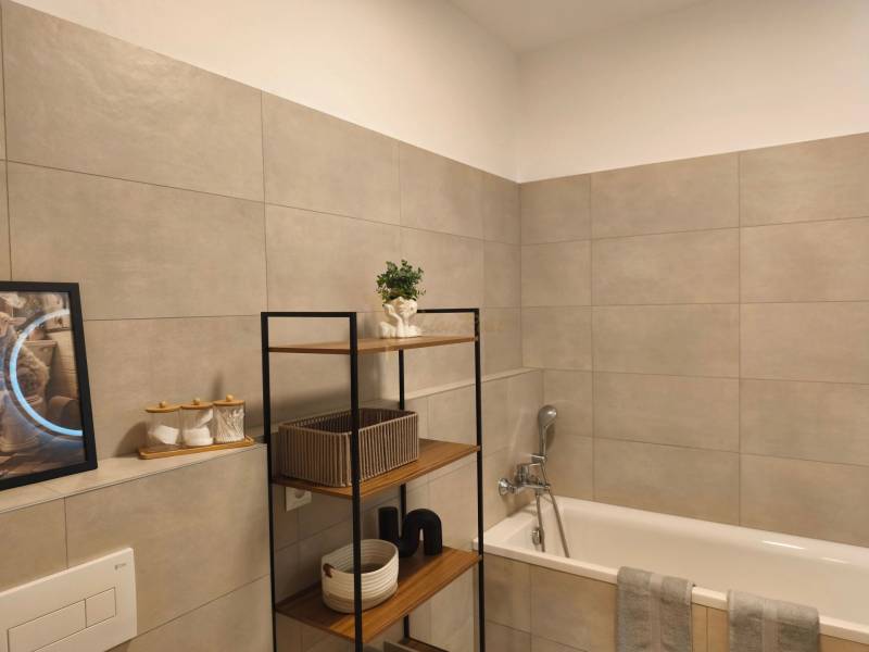 Fürdőszoba káddal és polccal egy kétszobás lakásban, dekoráció és tároló kosarak.