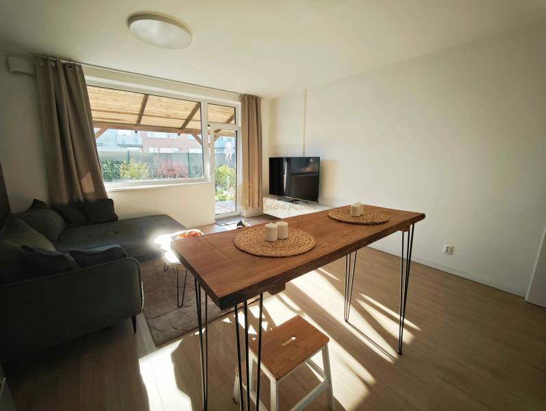 Nappali kanapéval és asztallal egy kétszobás lakásban, fa dekoros padlóval.