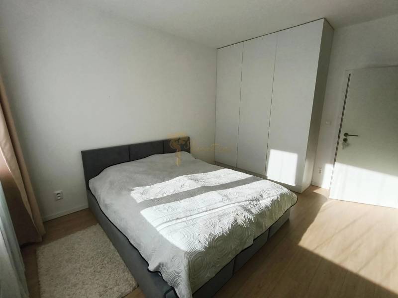 Hálószoba egy kétszobás lakásban ággyal, beépített szekrénnyel, fa dekoros padlóval.