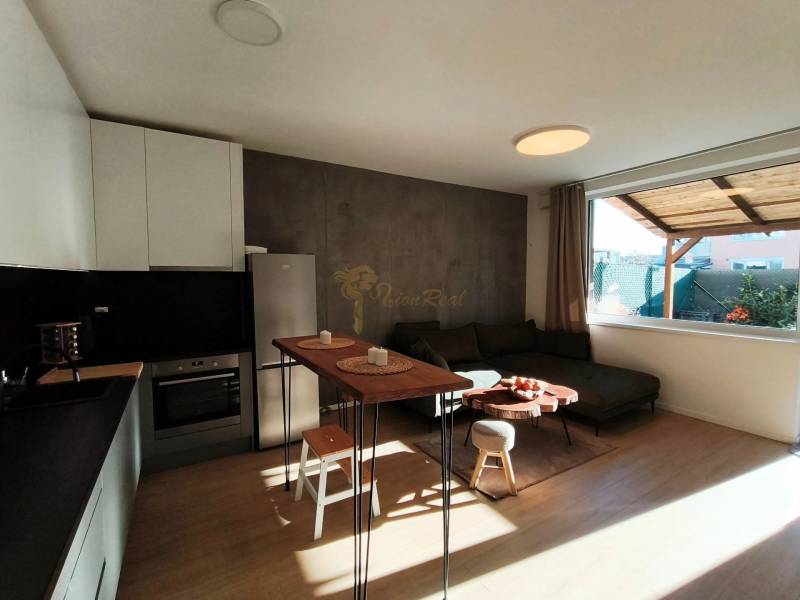 Nappali egy kétszobás lakásban konyhasarokkal és fa dekorációjú padlóval.