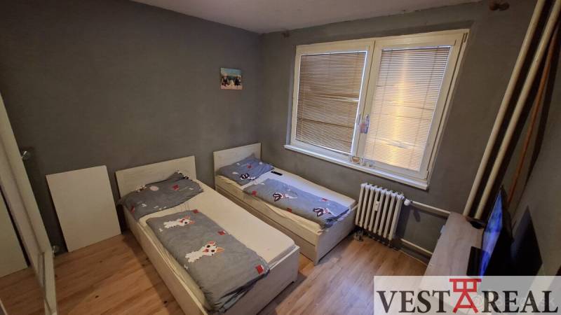 Gyerekszoba két ággyal és fa dekorációjú padlóval egy háromszobás lakásban.