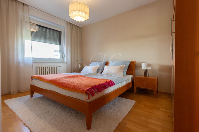 Hálószoba franciaággyal, éjjeliszekrénnyel és fa dekorációjú padlóval egy 4 szobás lakásban.