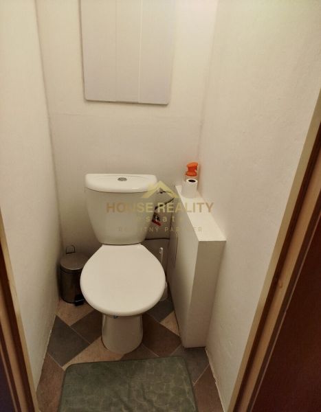 Egy szobás lakás fürdőszobája csempével és higiéniai felszereléssel.