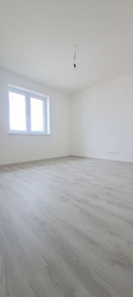 Üres szoba fehér falakkal és fa mintázatú padlóval egy családi házban.
