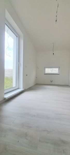 Családi ház belső tere fa dekorációjú padlóval és nagy ablakkal.