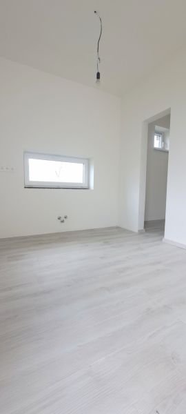 Szoba egy családi házban fa dekoros padlóval és kis ablakkal.