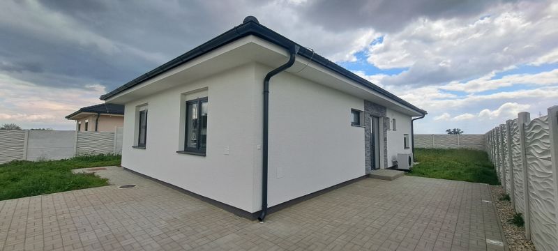 Családi ház Topoľnicán fehér homlokzattal és kövezett terasszal.