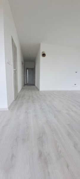 Családi ház belső tere fehér falakkal és fa dekorációjú padlóval.
