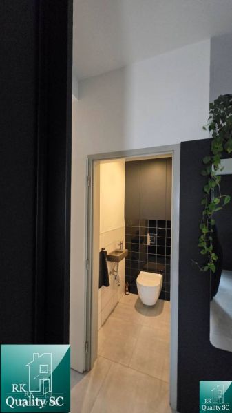 WC egy családi házban fekete csempével és világos padlóval.