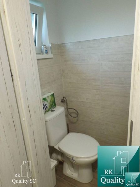 WC a fahatású padlóval és bézs csempével rendelkező házban.