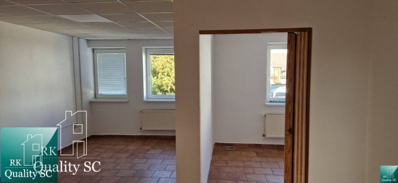 Családi ház belső tere terrakotta padlóval, fehér falakkal és ablakok alatti radiátorokkal.