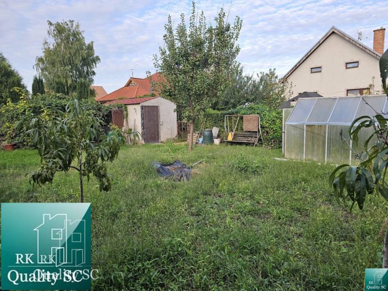 A családi ház kertje Tureň községben, gyep, üvegház és fák.