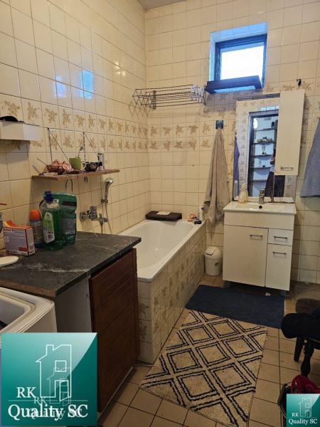 Családi ház fürdőszobája káddal, szekrénnyel és csempézett falakkal.