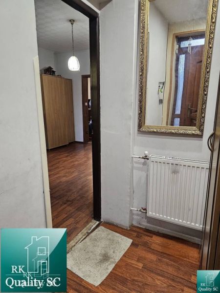 Családi ház belső tere fa dekorációjú padlóval, tükörrel és radiátorral.