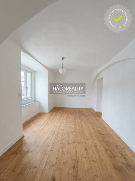 Világos szoba íves mennyezettel és fa mintázatú padlóval egy háromszobás lakásban.