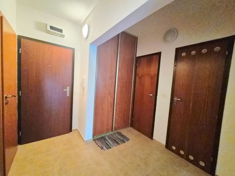 Előszoba egy kétszobás lakásban, faajtókkal és csempével a padlón.