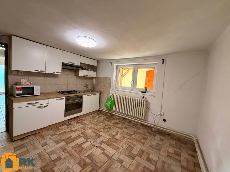 Családi ház konyhája csempével és fehér szekrényekkel.