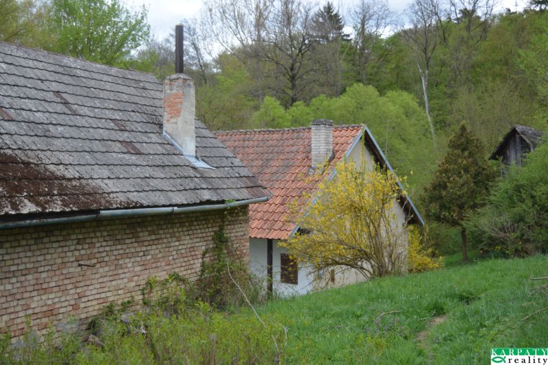 Bukoveci családi ház régi téglafallal, zöld környezettel és fákkal körülvéve.