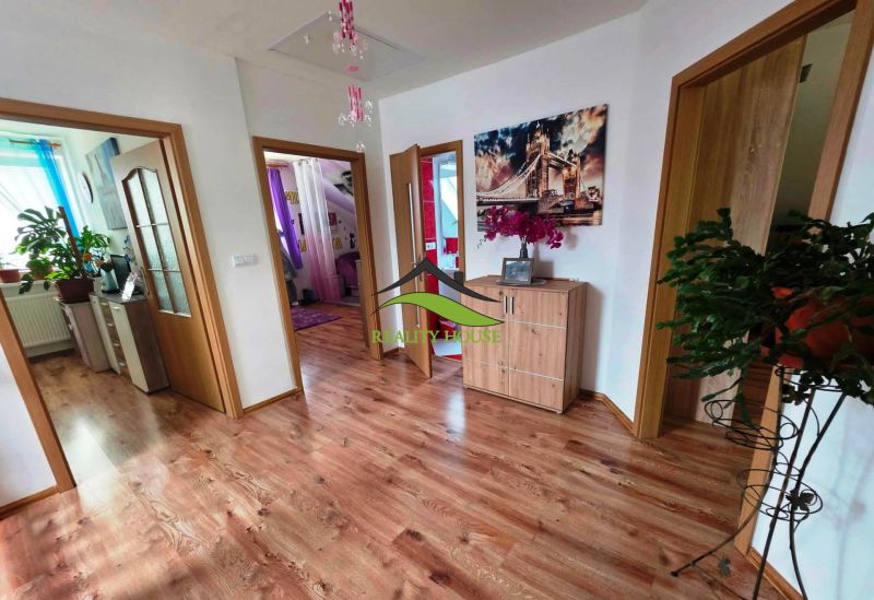 Családi ház belső tere fa dekorációjú padlóval és szobanövényekkel.
