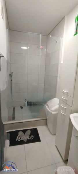 Fürdőszoba egy kétszobás lakásban tágas zuhanyzóval és fehér bútorokkal.