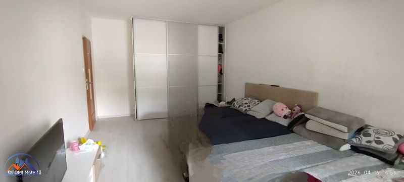 Hálószoba egy kétszobás lakásban tolóajtós szekrénnyel és ággyal, fa dekoros padlóval.